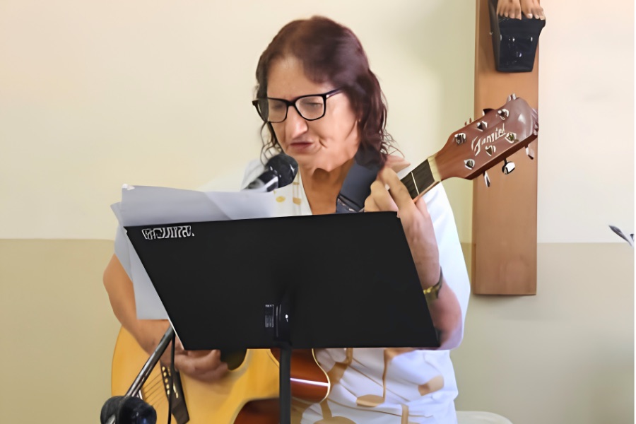 Amélia cantando e tocando violão na igreja